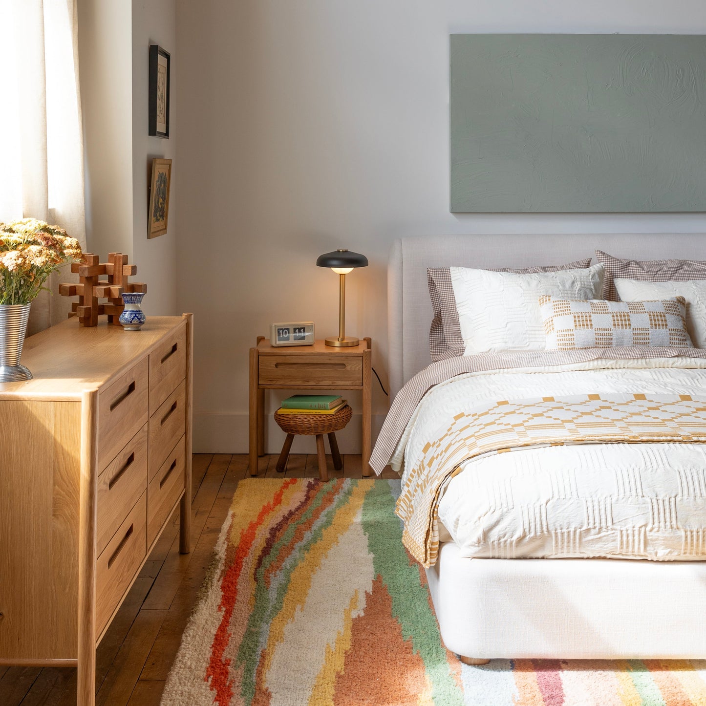 Bed styled with Woven Tally Duvet Cover in natural, layered with patterned shams beside wooden dresser and nightstand lamp