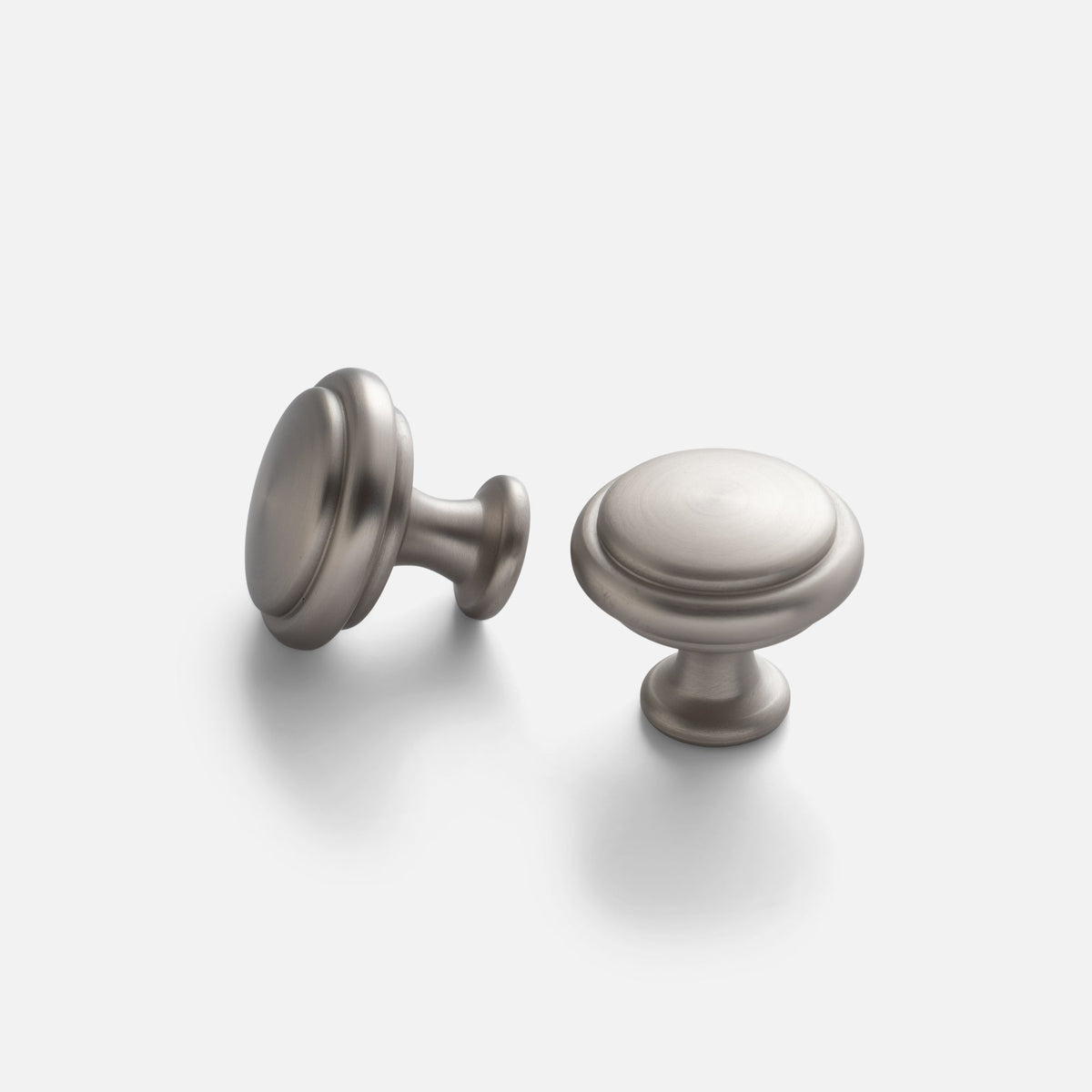 Angled views of the Whittaker Knob showcasing its traditional turned form and satin nickel finish on a light gray background