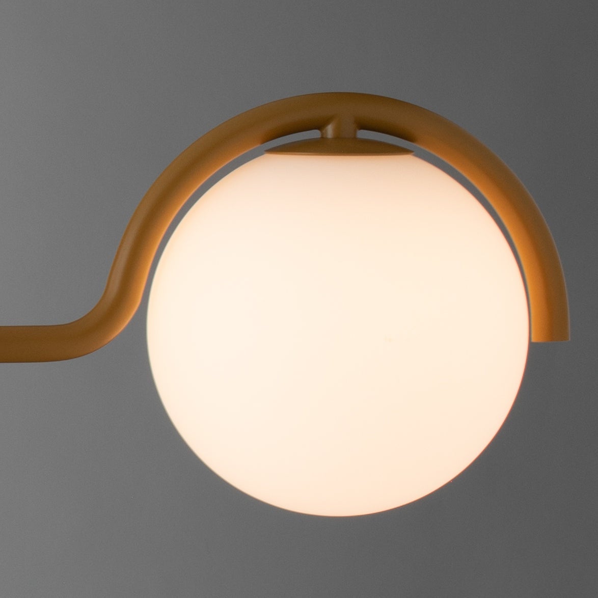 Close-up of Aurora Linear showcasing a glowing spherical light and curved frame against a gray background