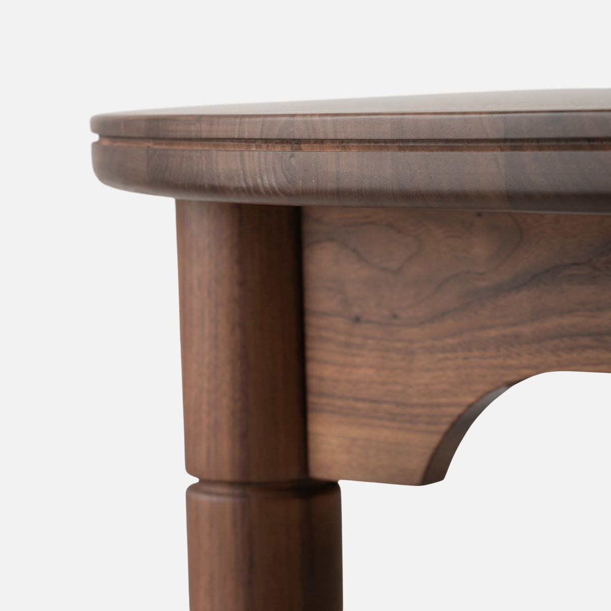 Close-up of the Willard Dining Table showcasing its rounded edge and classic apron against a white background