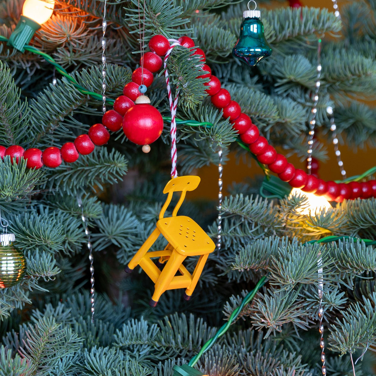 Front view of Utility Chair Ornament showcasing its yellow finish hanging on a decorated Christmas tree