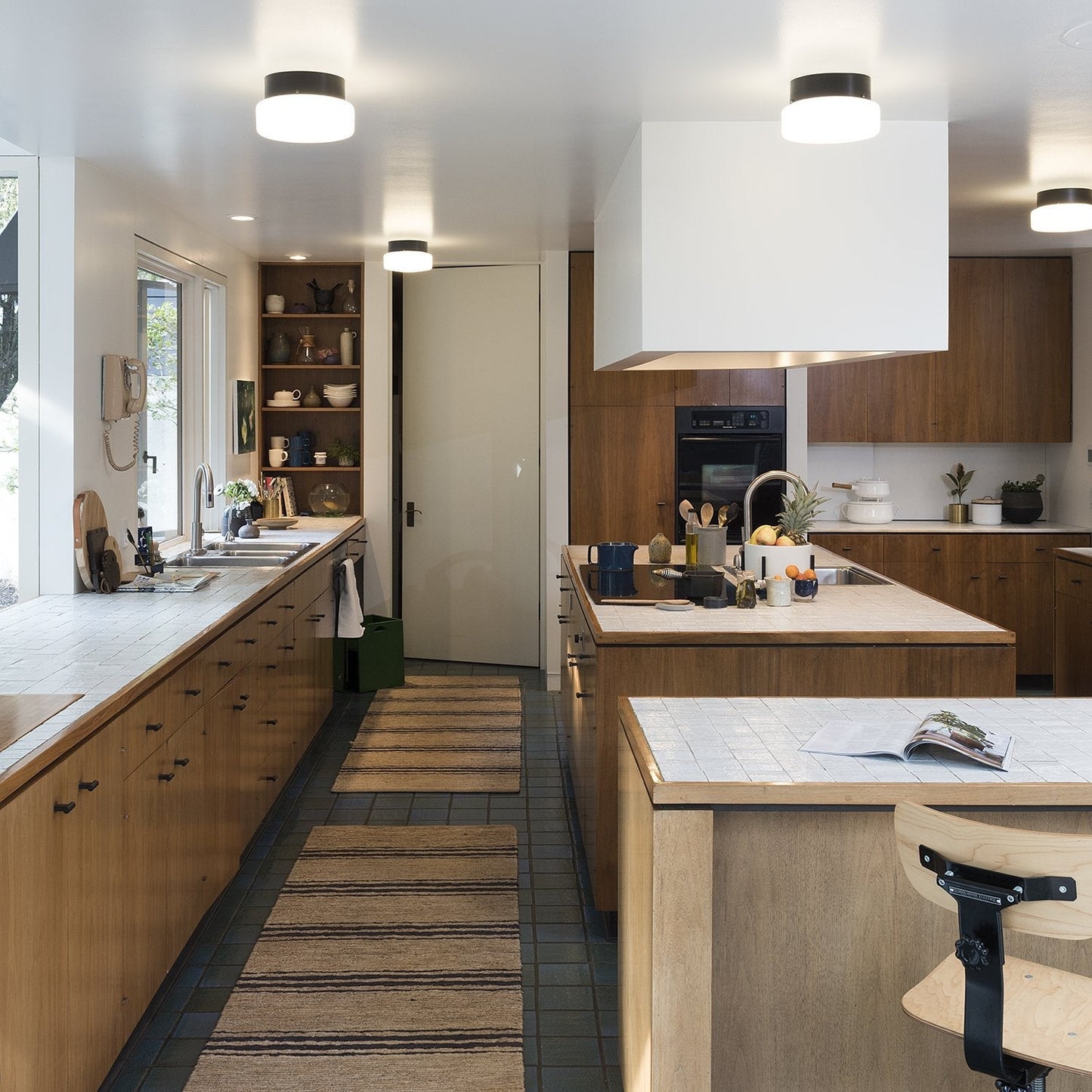Modern kitchen showcasing T pulls on wood cabinetry, pendant lights, and tiled countertops