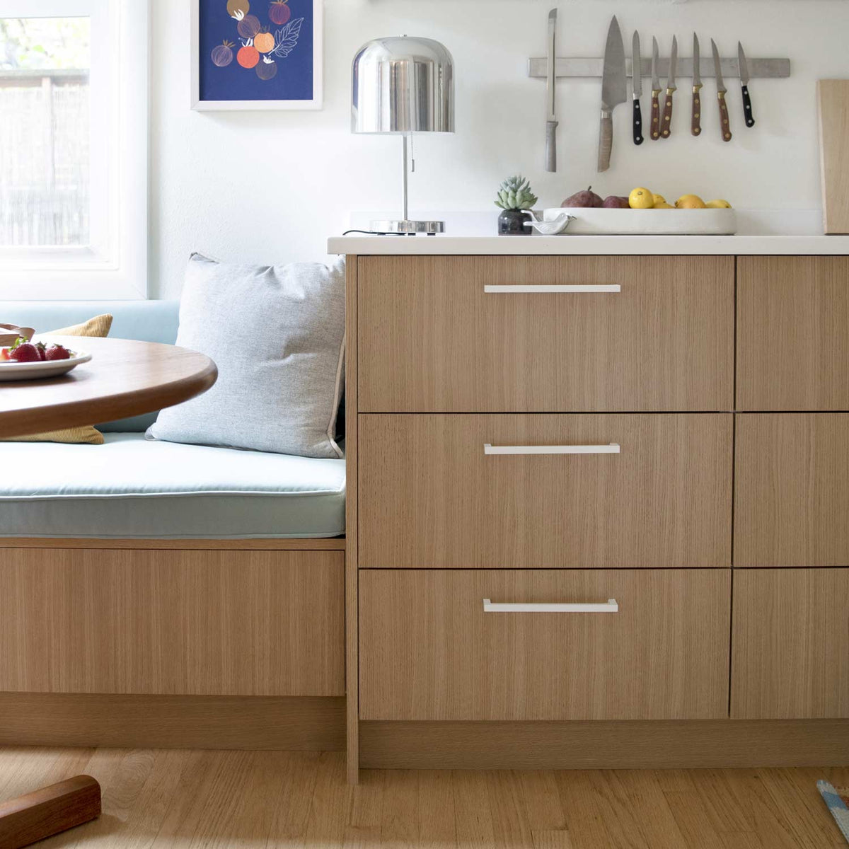 Edgecliff appliance pulls installed on wood kitchen drawers in a bright dining area