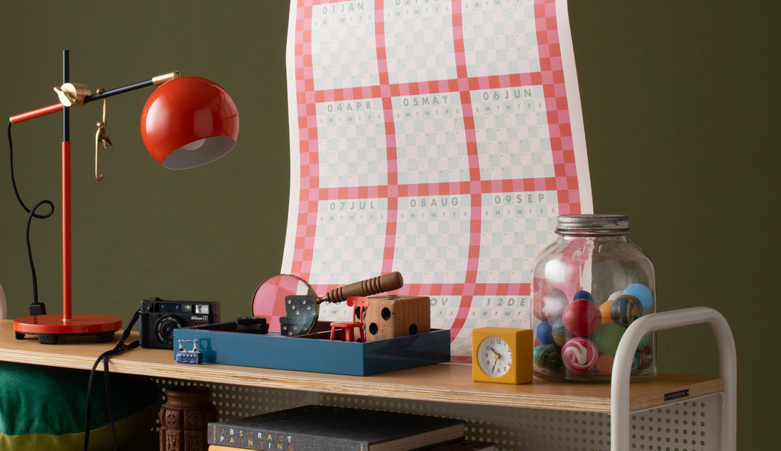 Nostalgic objects arranged on a console with a red lamp, colorful calendar, camera, toy-filled jar, and clock