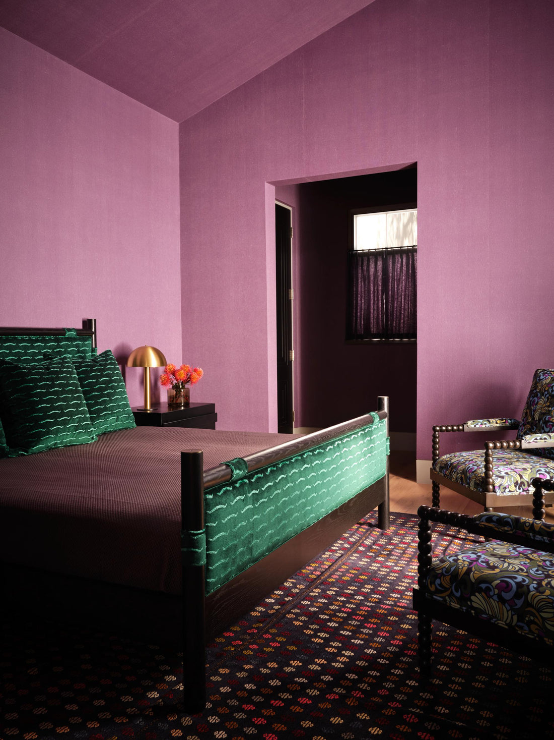 Colorful bedroom featuring a green patterned bed, patterned armchair, and purple walls