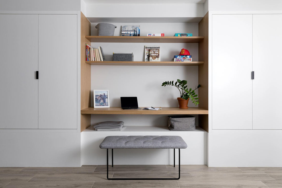 Built-in shelving and white cabinets frame a gray upholstered bench in a modern Austin home