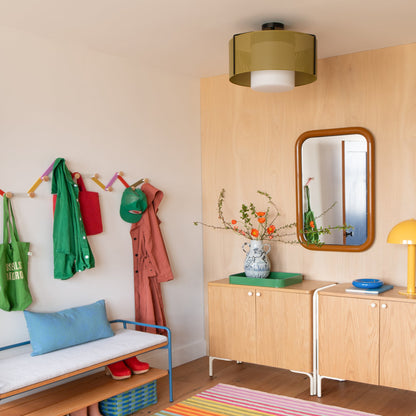 Swell 20-inch flush mount ceiling light with perforated olive metal shade and frosted glass diffuser installed in an entryway with a wood cabinet, mirror, and colorful hooks