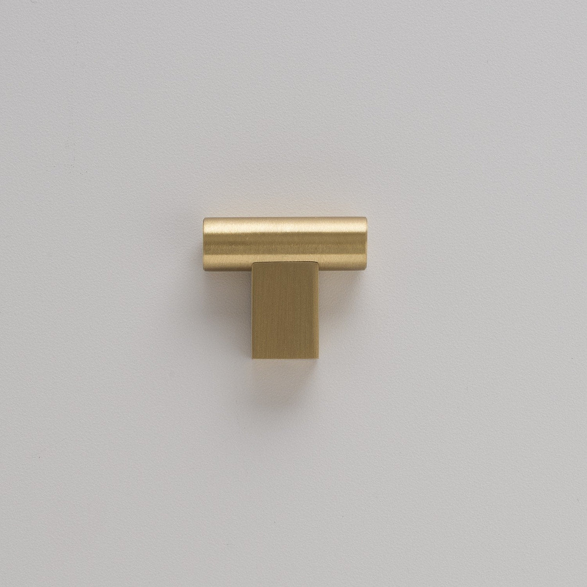 Front view of T Pull showcasing its natural brass finish against a light gray wall