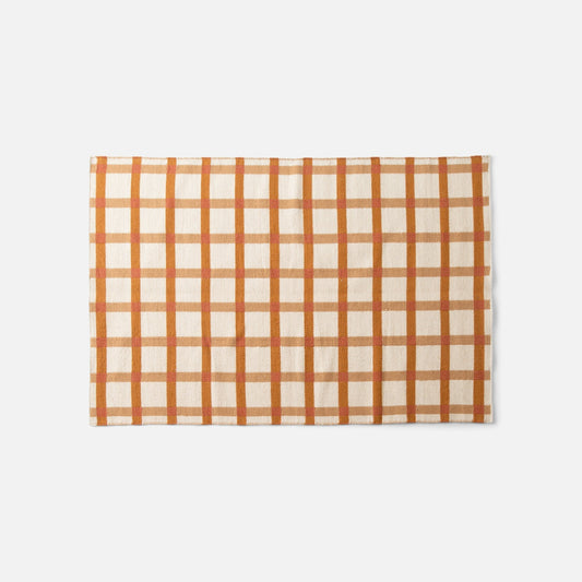 Top edge of Plaid Wool Reversible Rug showcasing orange-and-tan plaid handwoven wool on white background