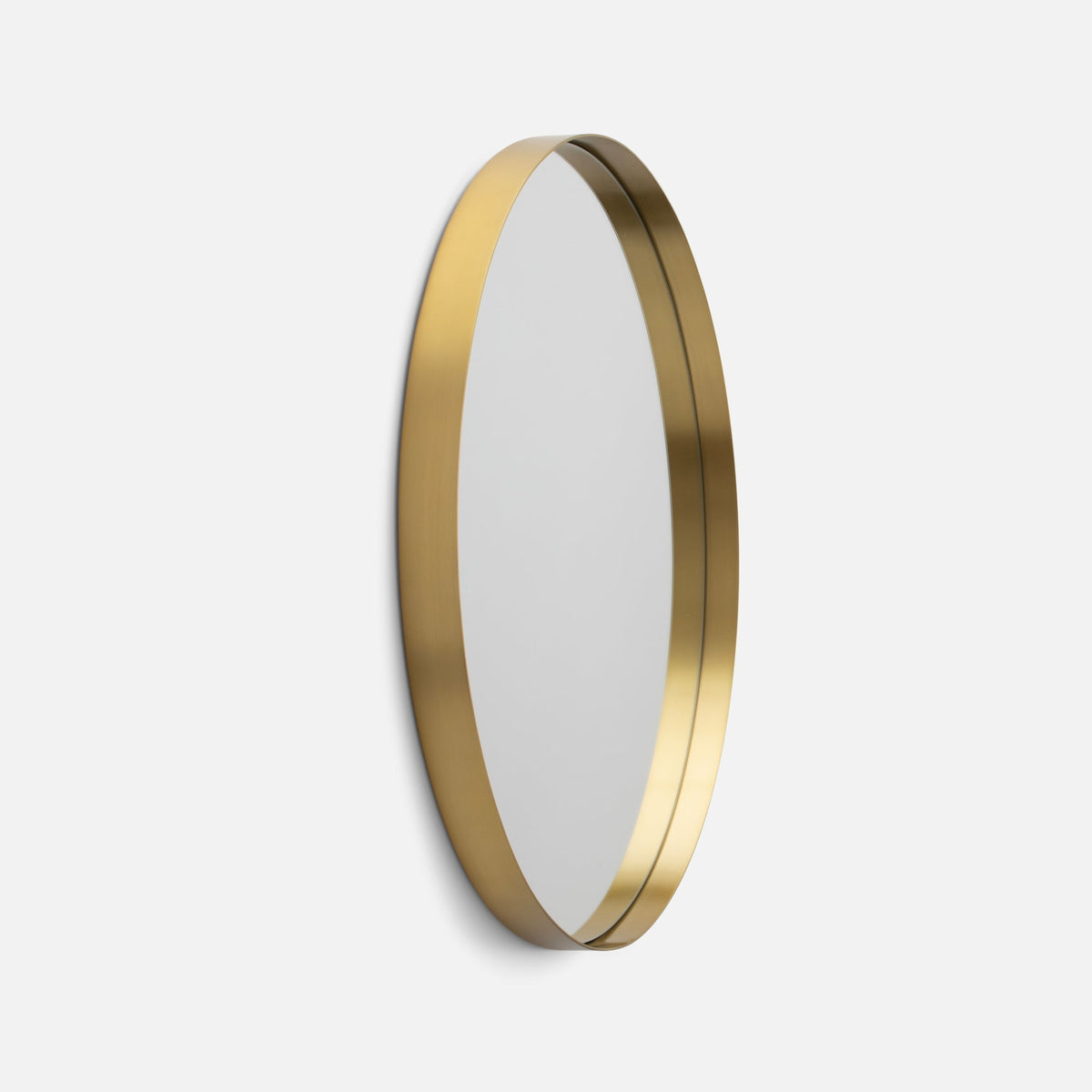 Angled view of Leo Mirror showcasing its brass frame and oval shape against a light gray background