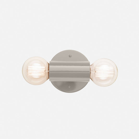 Front view of Cylinder Double Sconce showcasing two globe bulbs and a slender gray fixture on a light background