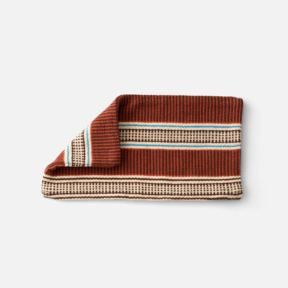 Folded view of Anders Pillow Cover showcasing a brown, cream, and blue striped woven pattern with a white background