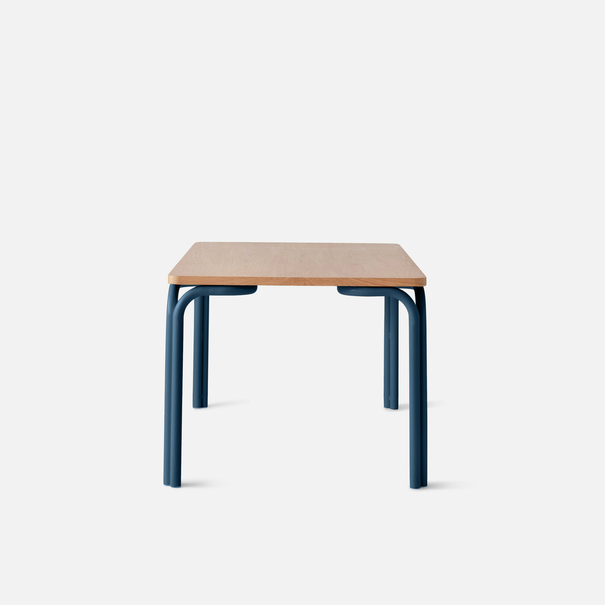 Front view of Forma Dining Table showcasing oak veneer top and blue powder-coated steel legs with a white background