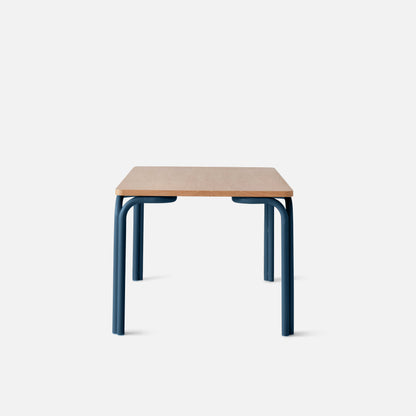 Front view of Forma Dining Table showcasing oak veneer top and blue powder-coated steel legs with a white background