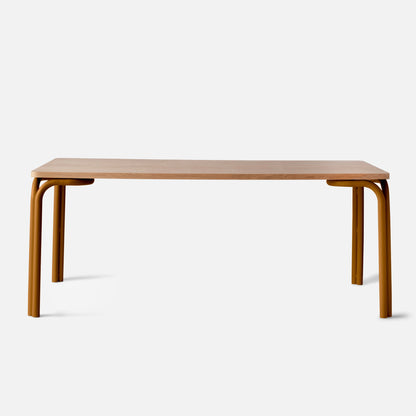 Front view of Forma Dining Table showcasing an oak veneer top and curved mustard steel legs with a white background