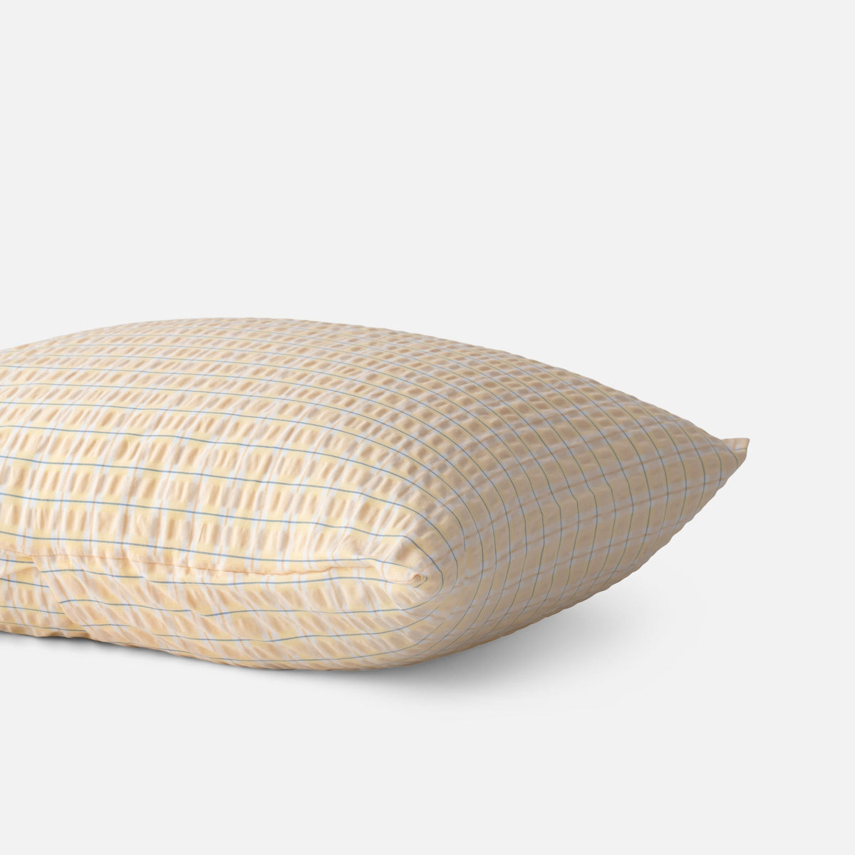 Side view of Seersucker Check Sham showcasing yellow with natural cotton seersucker check texture on a light gray background