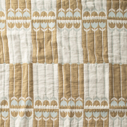 Close-up of Tulbend Quilt showcasing stitched tan, cream, and pale blue tulip patterns