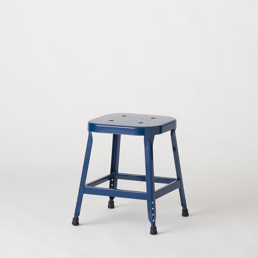 Three quarter view of the Schoolhouse Utility Stool 26 inch in indigo gloss, showing its welded steel frame and stamped seat