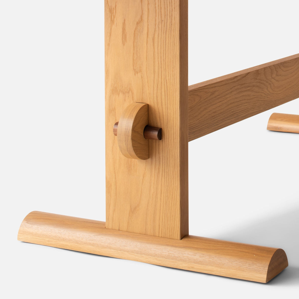 Close-up view of Darrow Dining Table showcasing contrasting walnut stretcher joinery with a white background