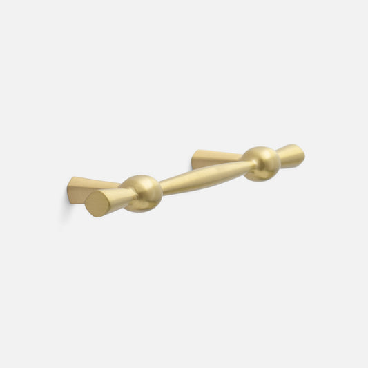 Three-quarter view of Eleanor Pull showcasing its curved bow tie design in natural brass with a light gray background