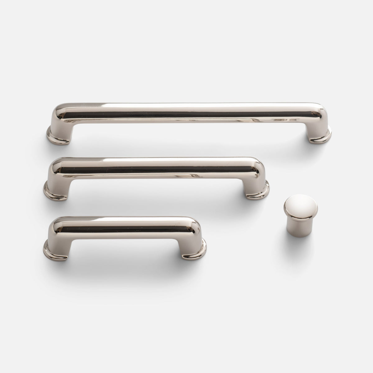 Front view of Remy Knob showing its soft-curved solid brass design alongside matching pulls on a white background