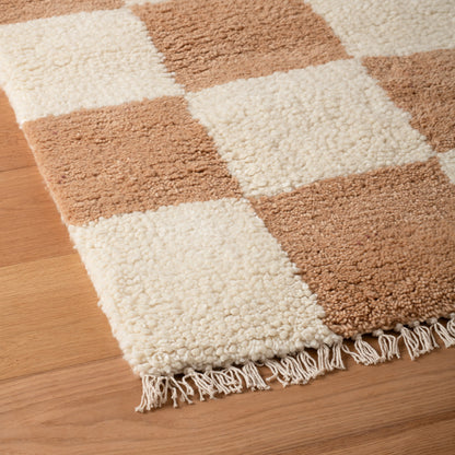 Close-up of Schoolhouse x Clare V. Jacques Shag Wool rug showing cream and tan check pattern, high-pile wool texture and fringe on wood floor