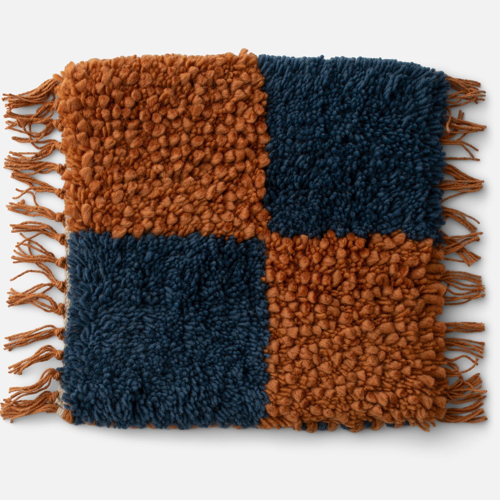 Close-up of Jacques Shag Wool Rug showcasing rust and navy checker pattern, high-pile wool shag texture and fringe on white background
