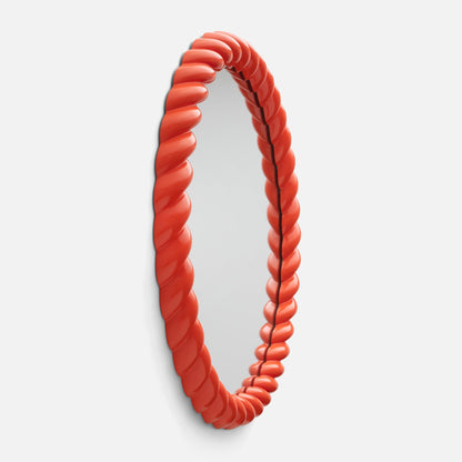 Angled view of Fernand Mirror showcasing its twisted Persimmon-Gloss frame on a white background