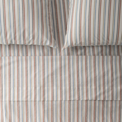Close-up of Fresh Stripe Sheet Set showcasing classic tawny, olive, indigo, and black stripes on a bed