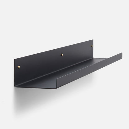 Three-quarter view of Brake Angle picture ledge showcasing black satin steel and brass mounting hardware on a white background