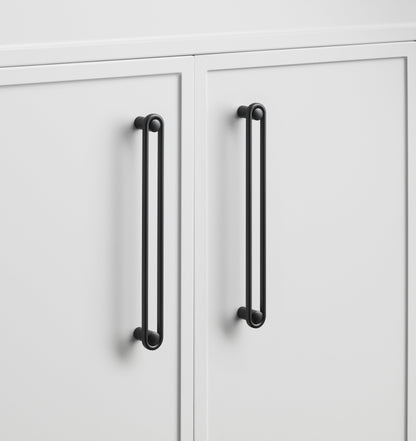 Close-up of Landon Pull showcasing its elongated black bar design on white cabinet doors