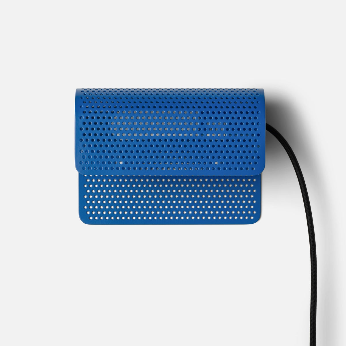 Front view of Swell Plug-In Sconce showcasing Cobalt-Satin perforated steel shade and black cord on white background