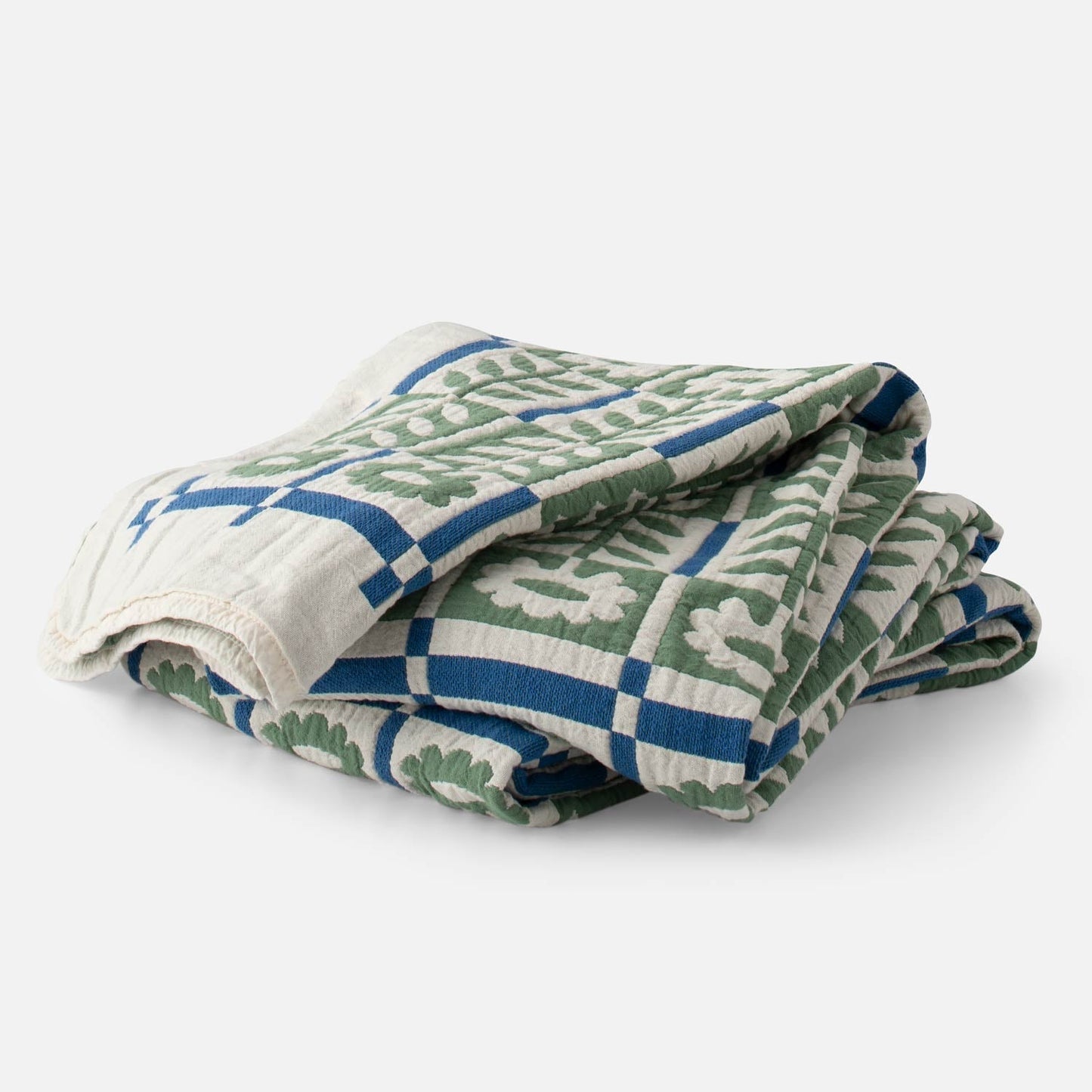 Folded Stillwater Floral Quilt showing green mirrored florals and blue grid with jacquard texture on white background