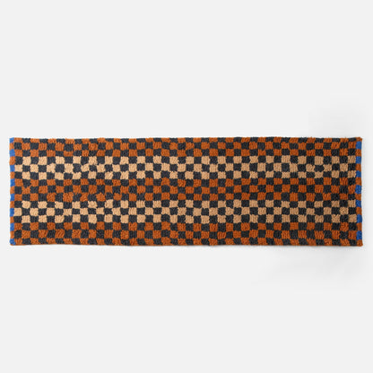 Top edge view of Felix shag wool rug showcasing butterscotch and navy checkerboard pattern and high-pile texture on white background