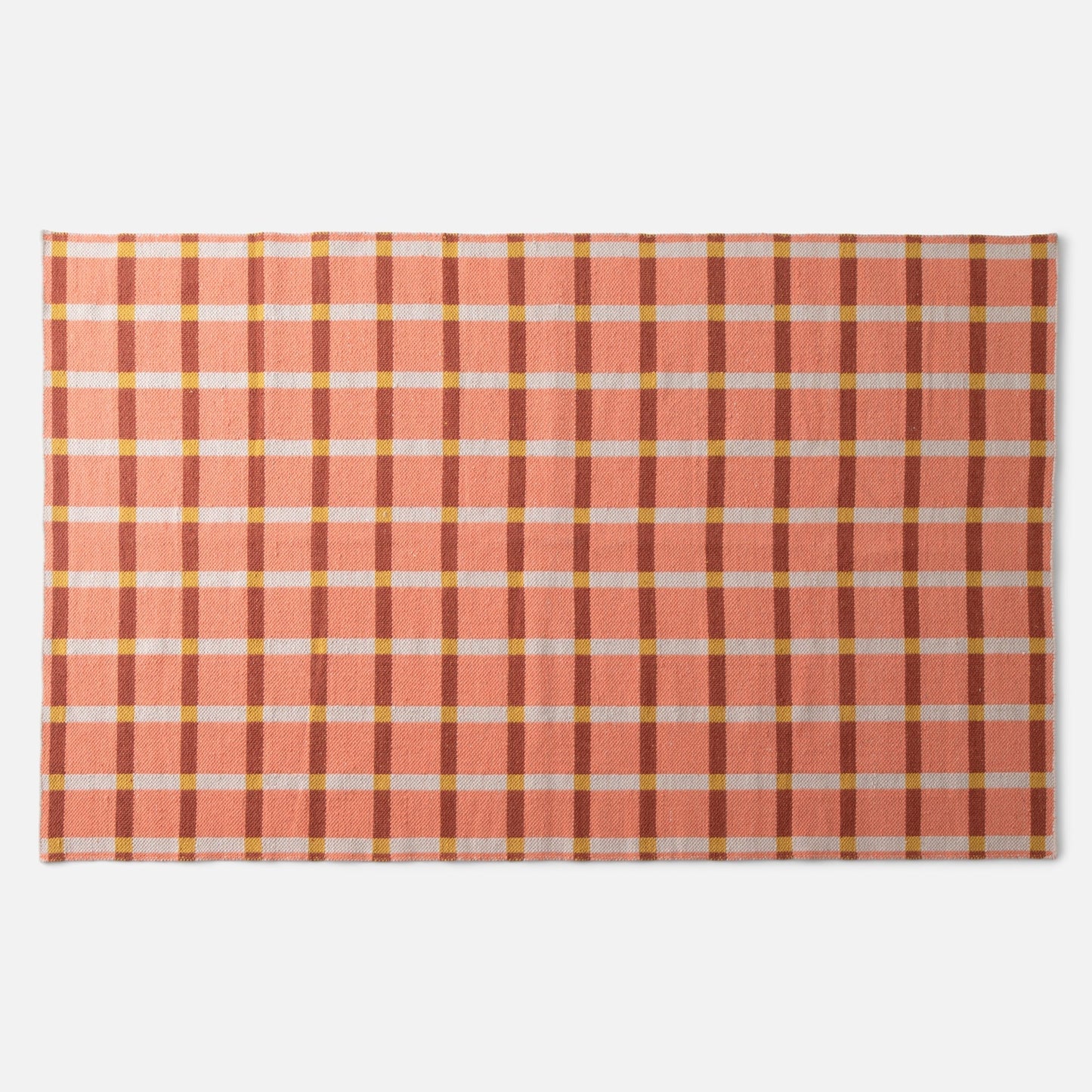 Top-down view of Plaid Wool Reversible Rug showcasing peach-and-rust plaid with white and yellow checks on a white background
