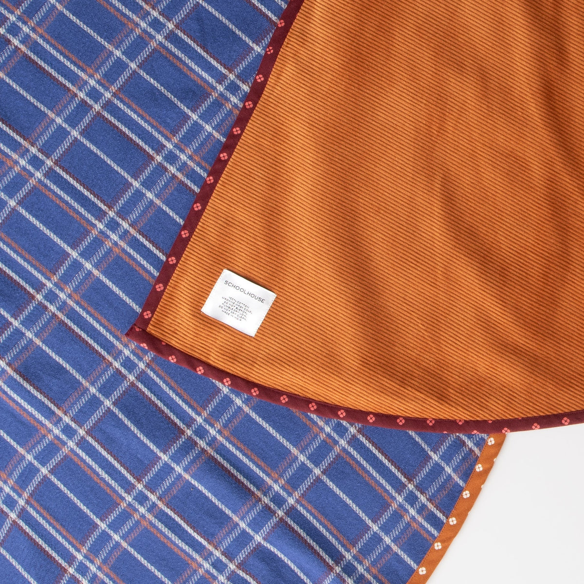 Close-up of Haberdasher’s Tree Skirt showcasing cobalt plaid, orange corduroy, and patterned trim on a white background