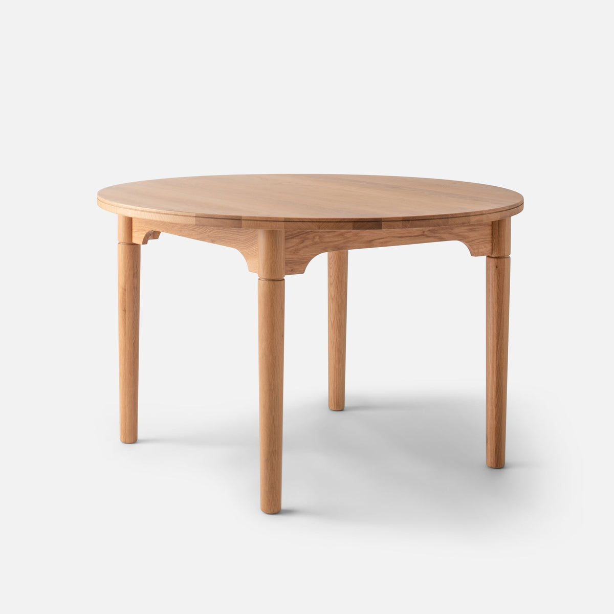 Three-quarter view of Willard Dining Table showcasing gently tapered legs and softly rounded edge on a light background