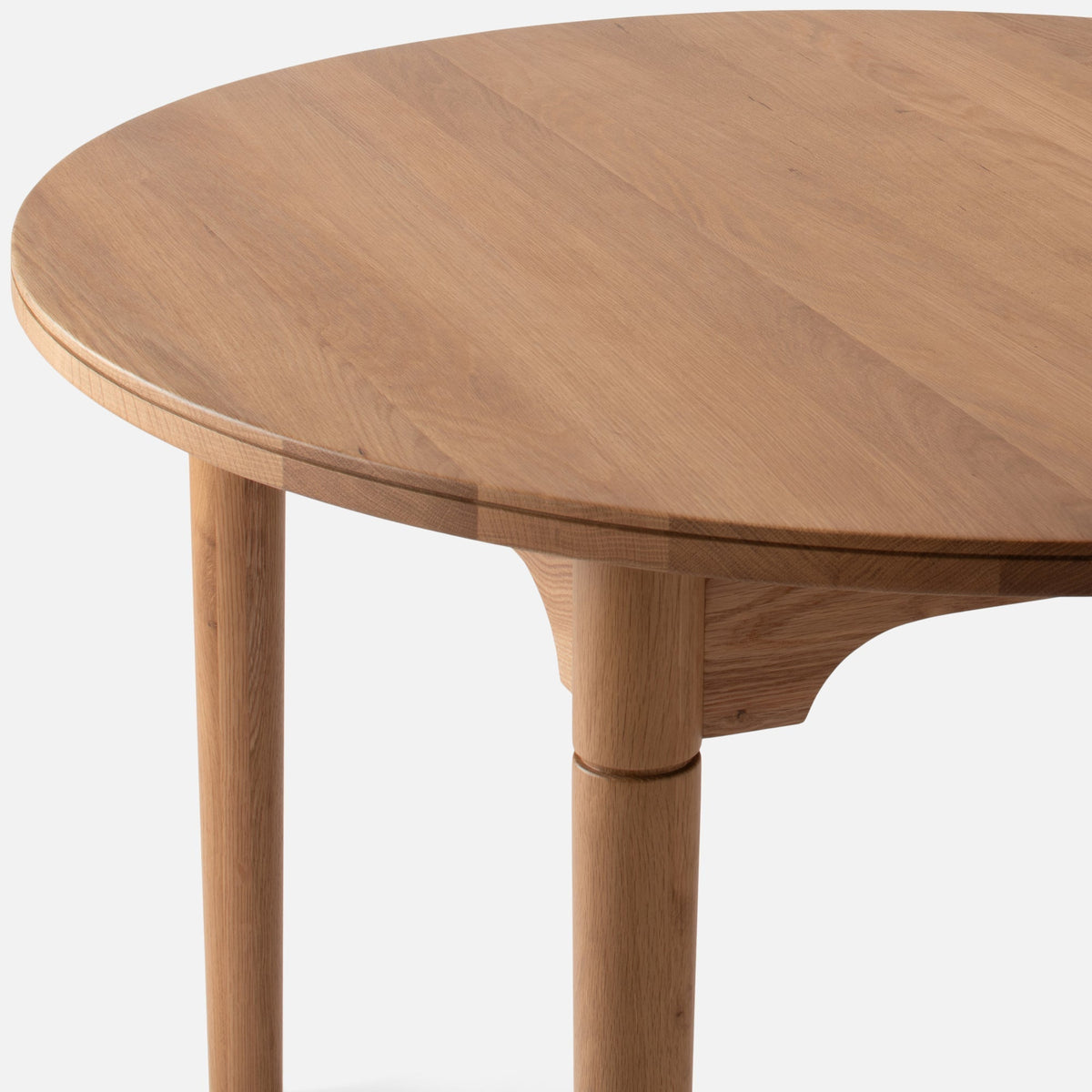 Front close-up of Willard Dining Table showcasing solid oak tabletop, softly rounded edge, and classic apron with white background