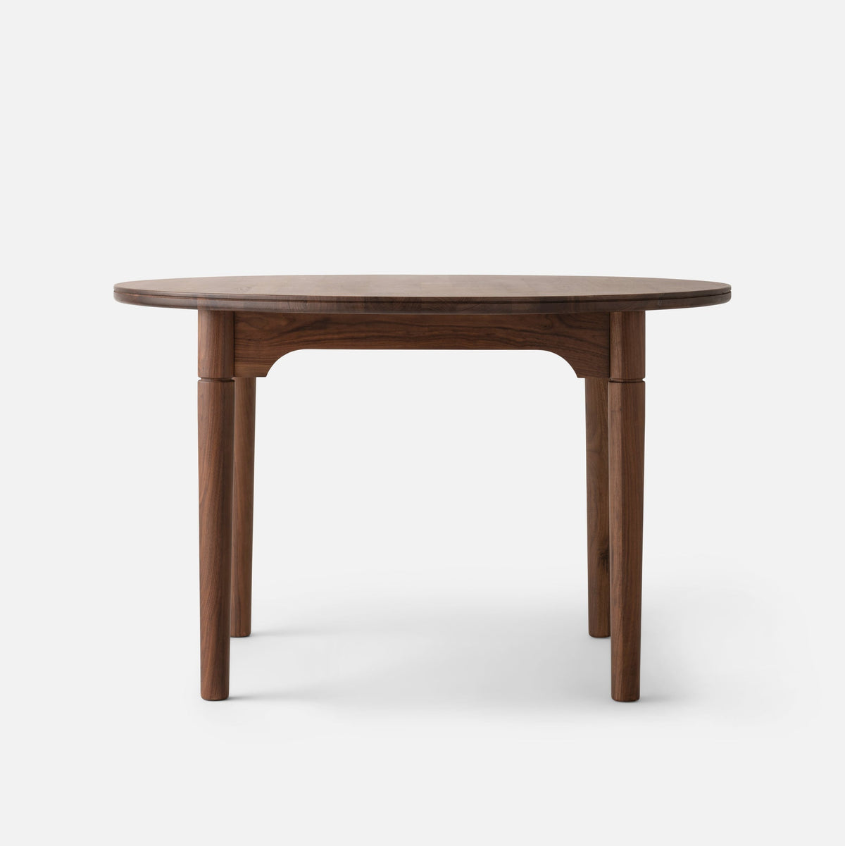 Front view of Willard Dining Table in walnut showcasing its softly rounded edge, classic apron, and tapered legs