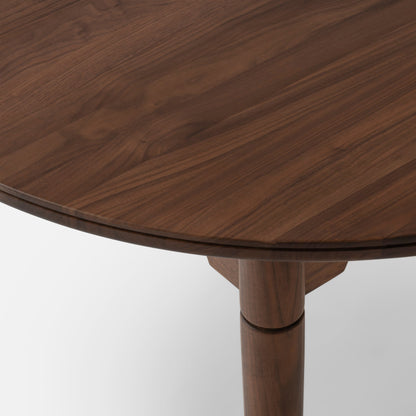 Close-up view of Willard Dining Table showcasing walnut grain, rounded edge, and tapered leg against a white background