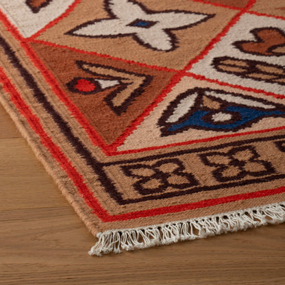 Close-up of Linnea Wool Flatweave Rug showcasing hand-drawn floral motifs, flatweave texture, and fringe on a wood floor
