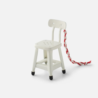 Three-quarter view of white Utility Chair Ornament with perforated seat and red-and-white hanging cord
