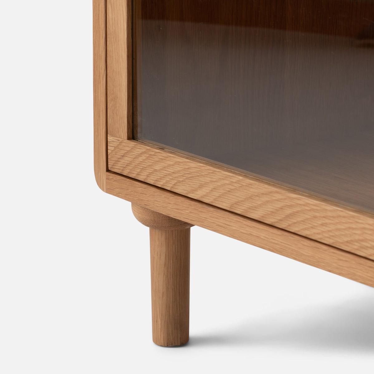 Close-up view of Peggy Cabinet showcasing its wood frame, rounded corner, and leg against a white background