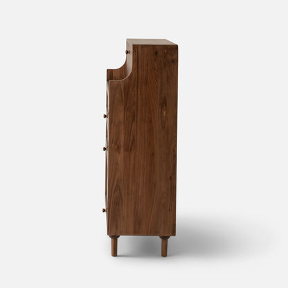 Side view of Peggy Cabinet showcasing its tall wooden form, legs, and brass knobs against a white background
