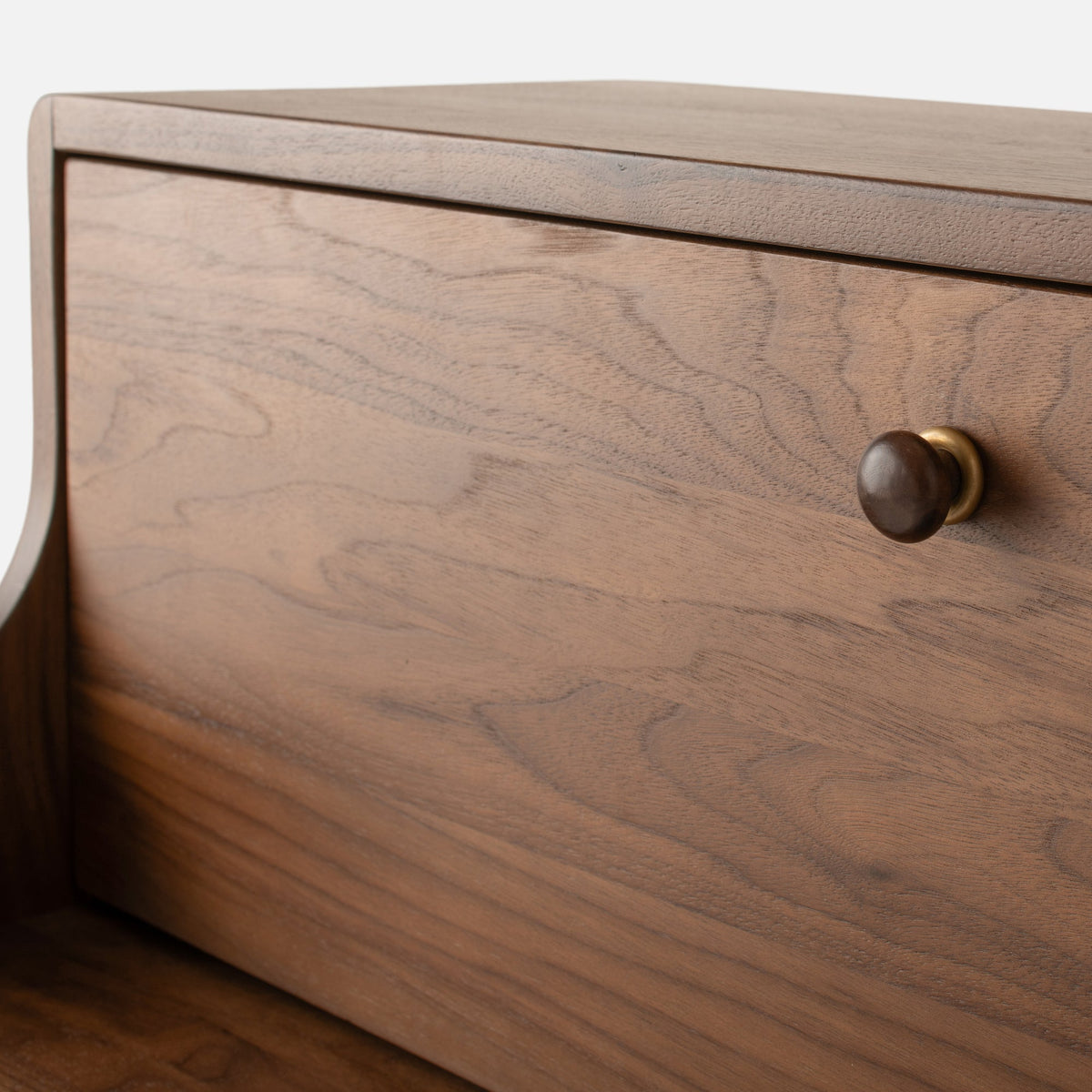 Close-up view of Peggy Cabinet showcasing its wood-grain front and round drawer knob with a light background