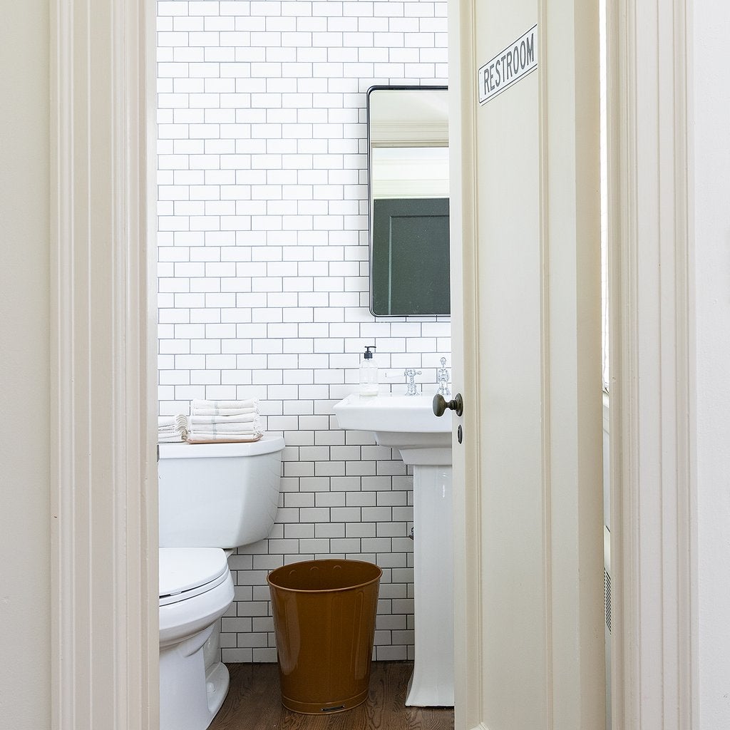 White Leo Mirror above a bathroom sink, viewed through an open doorway