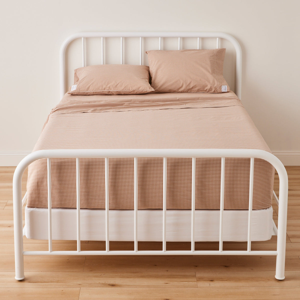 Front view of Gingham Pillowcase showcasing its gingham pattern on a bed with a white metal frame
