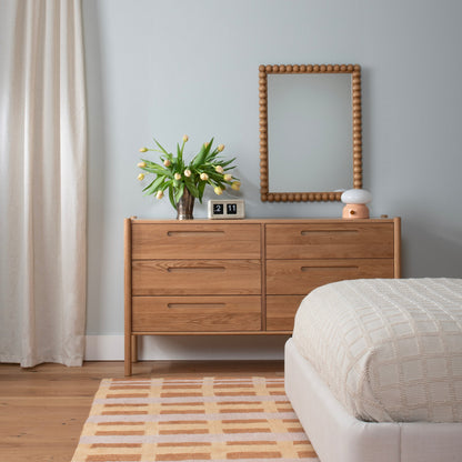 Terracotta Network tufted wool rug with a geometric pattern anchors a bedroom beside a wooden dresser and bed