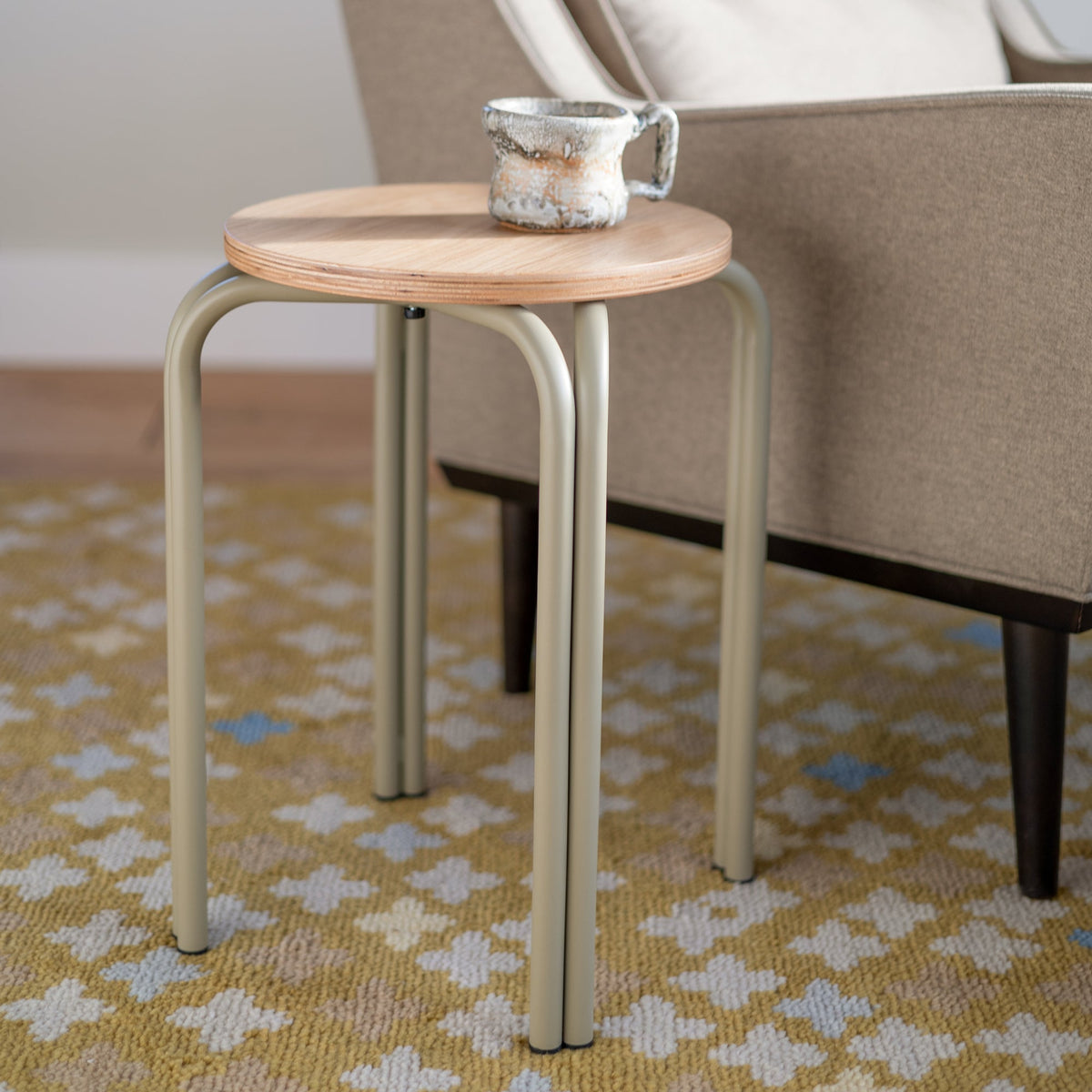 Close-up of Sundrop Rug showcasing graphic tossed flowers on a vivid chartreuse background beneath a side table and chair
