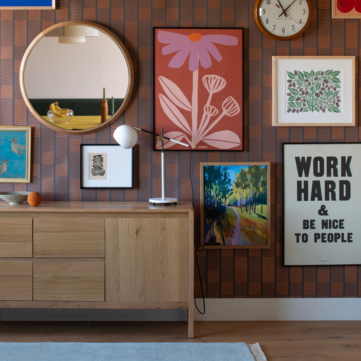 Isaac Desk Lamp on a wood credenza in a colorful room with patterned wallpaper and framed artwork